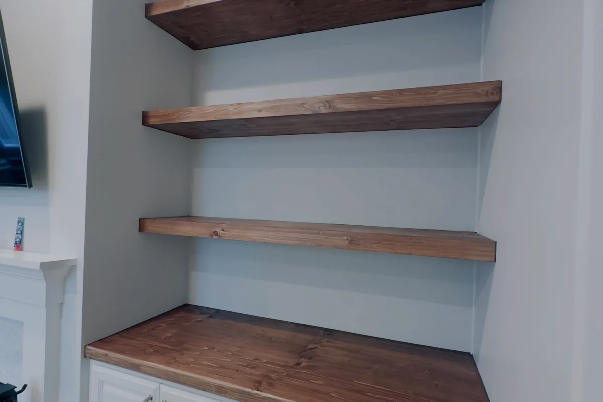 Built-in floating wood shelves above white cabinets in St. Petersburg